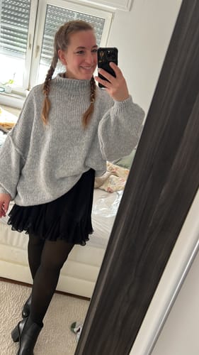 Kundin trägt die schwarze THERMO-Strumpfhose als Teil eines Outfits mit Rock und Pullover.