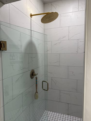 Customer's gold 12 Inch Rain Shower Head installed in a modern, tiled walk-in shower.