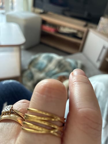 Close-up of a reviewer's hand wearing a textured, multi-band gold ring.