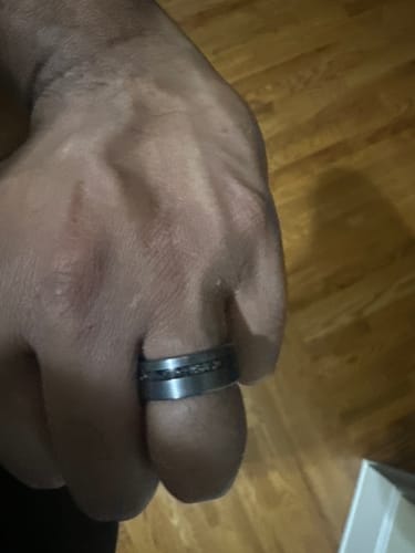 Close-up of a reviewer's thumb wearing The Thor ring with its dark meteorite inlay.