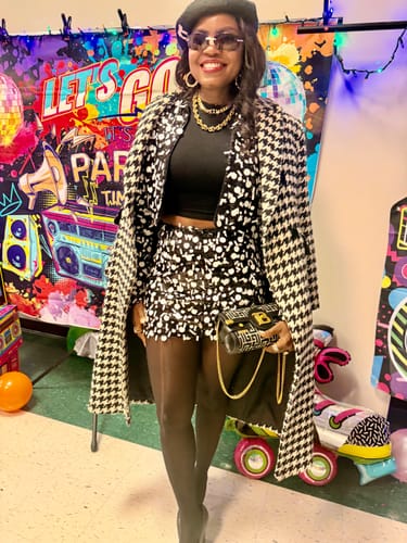 Reviewer at a party, wearing the matching sequin mini skirt from the collection with a long coat.
