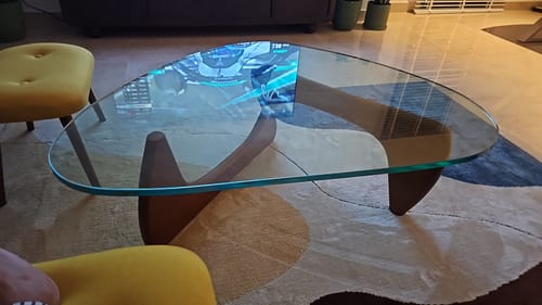 Customer's Noguchi solid wood coffee table with a thick glass top and sturdy wooden base in a living room.