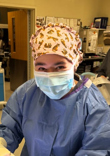 Customer wearing the slouchy, pink DuoStyle Scrub Hat with a tiger pattern in a medical office.