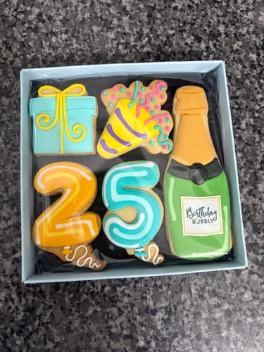 Reviewer's Birthday Balloon Biscuit Box showing colorful, decorated biscuits for a 25th birthday in its open packaging.