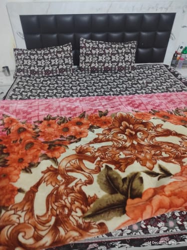 Customer's Flo Mattress Ergo on a bed with a dark headboard, made with patterned sheets and a colorful comforter.