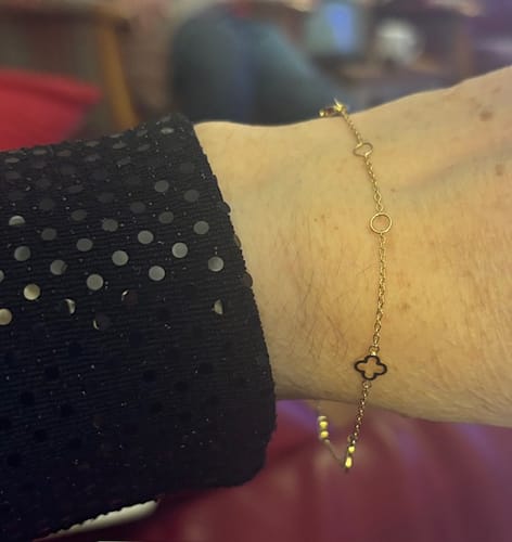 Reviewer wearing the delicate Multi Clover Bracelet on their wrist next to a sparkly black sleeve.