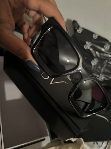 Un cliente sostiene las gafas de sol Ferrara Classic negras sobre su caja.