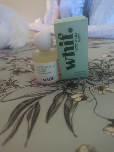 Customer's Patchouli Muse perfume bottle and its light green box sitting on a floral surface.