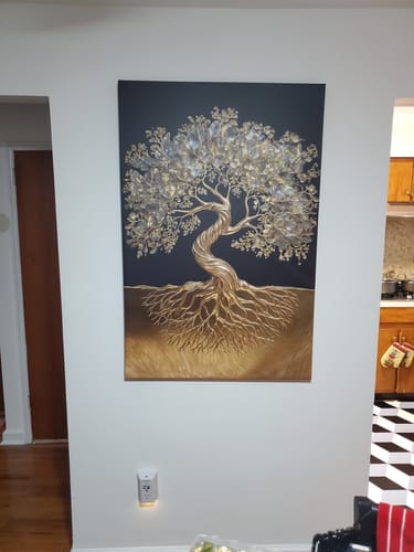 Reviewer's canvas painting of a gold tree of life with crystal leaves, hanging on a white wall in a room.