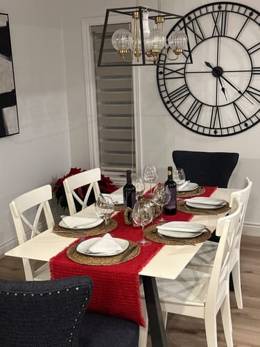 Reviewer's large black Roman numeral clock hanging on a white wall above a fully set dining table.