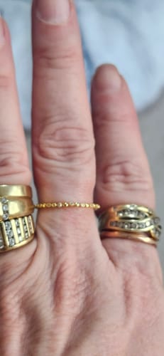 Customer wearing the dainty gold Illiana ring on their finger, stacked with two other rings.