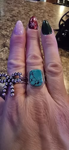 Reviewer's hand wearing the sterling silver ring with a large, square raw turquoise stone.