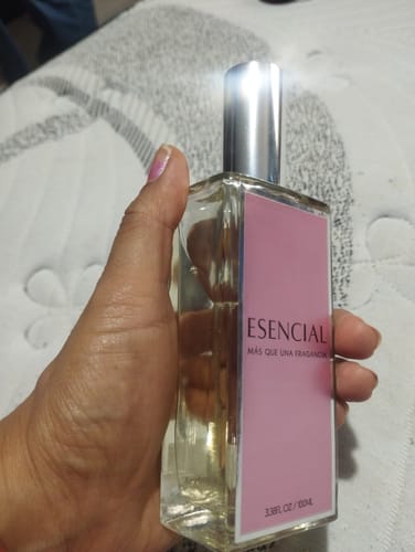 Cliente sosteniendo la botella de perfume M505 Esencial, mostrando la etiqueta rosa del producto.