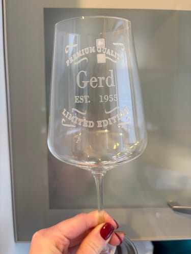 Eine Kundin hält das personalisierte Leonardo-Weinglas mit der Gravur „Gerd 1955“ in der Hand.