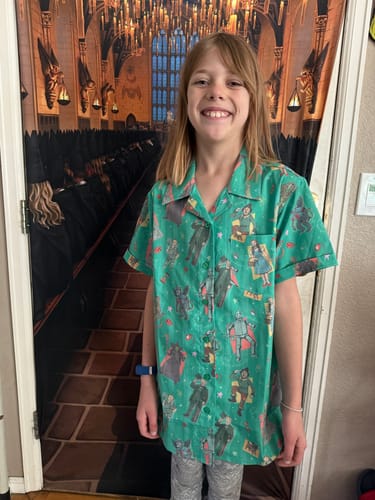 Customer showing the fit of the green, patterned "Off to See the Wizard" women's shirt.
