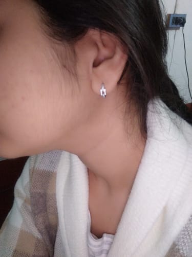 A reviewer's ear showing the fit of the silver Sparkling Loop Huggies Earring.