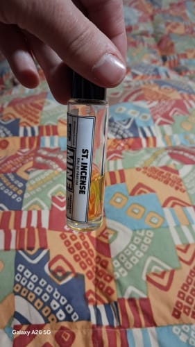 Recensore mostra un primo piano della boccetta di profumo ST INCENSE.