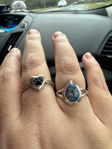 Reviewer's hand wearing the pear-shaped silver cremation ring with purple and turquoise details next to another ring.