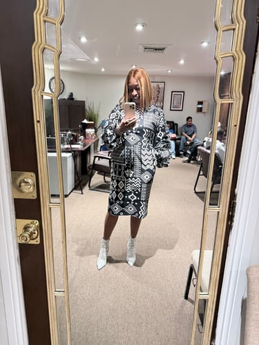 Reviewer taking a mirror selfie in the black and white Zora African Print Puff Sleeve Midi Dress.