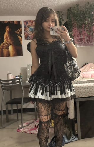 Reviewer taking a mirror selfie wearing the Melody Piano Doll Lolita skirt with black lace and a piano key design.