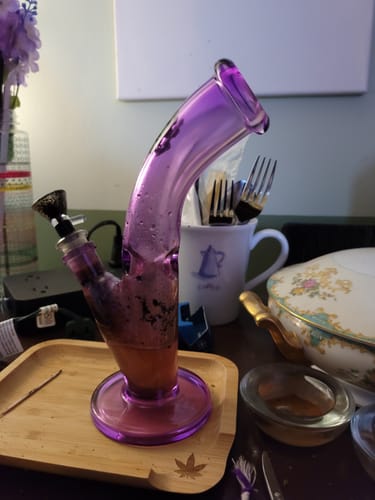 Customer's purple bent tube glass bong sitting on a wooden tray.