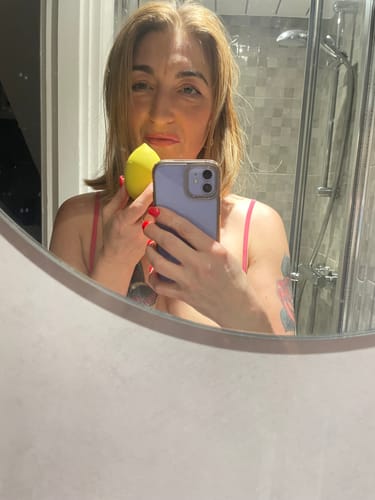 Reviewer takes a mirror selfie while holding the yellow Lem Clitoral Massager.