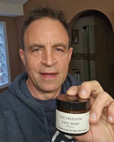 Reviewer holding a small jar of The Freedom Face Whip cream in a bathroom.