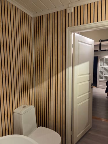 Kundes baderomsvegg dekket med lys Premium spiler kontaktplast ved siden av et toalett.