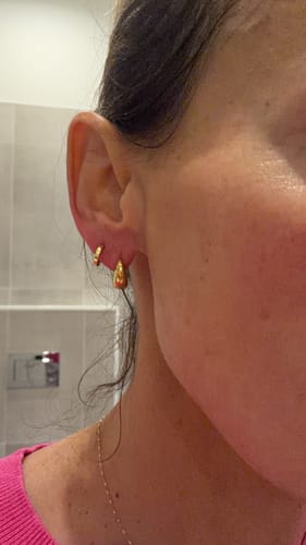Reviewer's close-up of the gold Mini Drop Huggies, showing how naturally they sit on the ear.