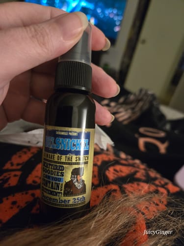 Customer holding a small, dark brown spray bottle of Belsnickel fragrance.