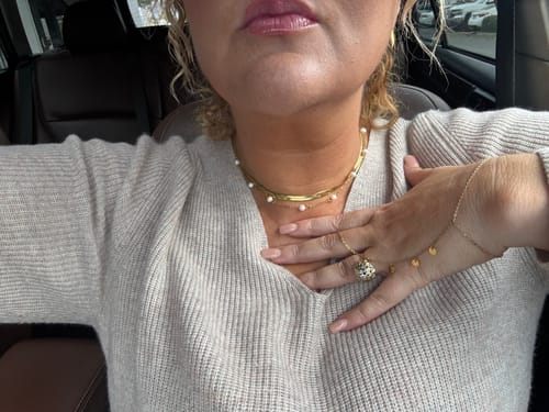 Customer wearing the Eira Handchain, a delicate gold chain with small disc charms, on their hand.