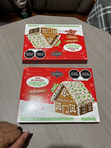 Cliente muestra dos cajas del Kit Casita de Galleta de Jengibre sobre una mesa.