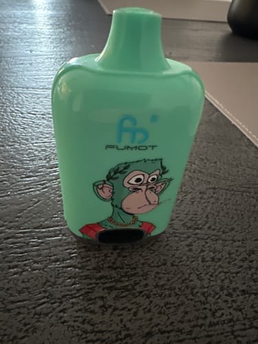 Customer's light green RAndM Tornado 9000 disposable vape with a cartoon monkey graphic, sitting on a dark surface.