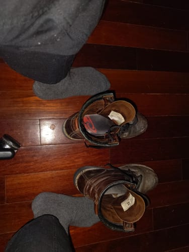 Reviewer wearing the thick, gray Men's Alpaca Socks with work boots on a wooden floor.