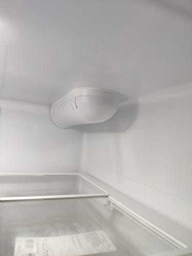 Customer shows the interior of a refrigerator with the housing where the Glacier Fresh water filter is installed.