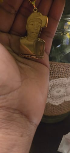 Customer holding their gold-colored Custom Photo Engraved Pendant, showing a portrait of a person.