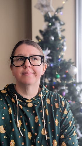 Reviewer wearing the dark green Star Wars hoodie with a festive gingerbread cookie pattern in front of a Christmas tree.