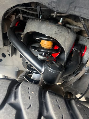 Close-up of a reviewer's black Upper Control Arms with red bushings installed on their Ford F150.