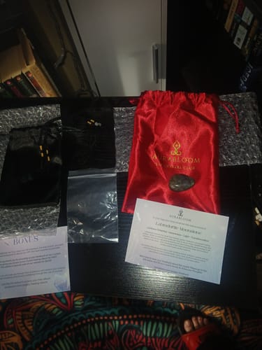 Customer's monthly crystal delivery laid out, showing a labradorite moonstone, a red pouch, and info cards.