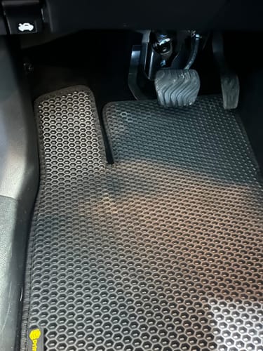 Klient pokazuje czarny dywanik samochodowy, idealnie dopasowany do podłogi po stronie kierowcy.