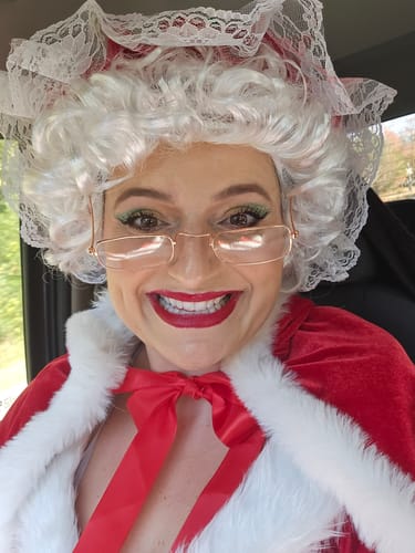 Reviewer in a close-up photo wearing the red velvet hooded cape with white trim and a red bow.