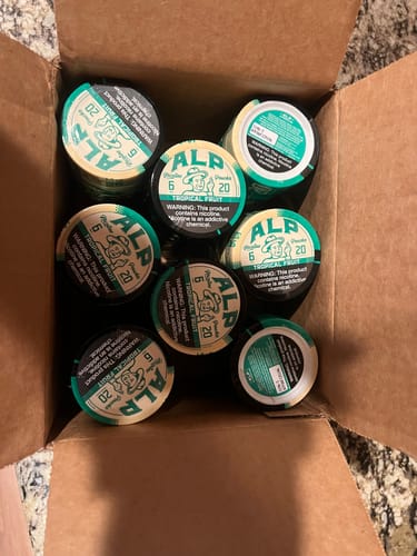 Customer's view inside a shipping box filled with tins of Tropical Fruit Nicotine Pouches.