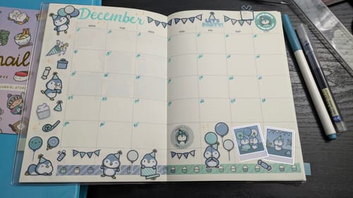 Customer's December planner spread decorated with cute Party Penguin stickers from the Sticker Subscription.