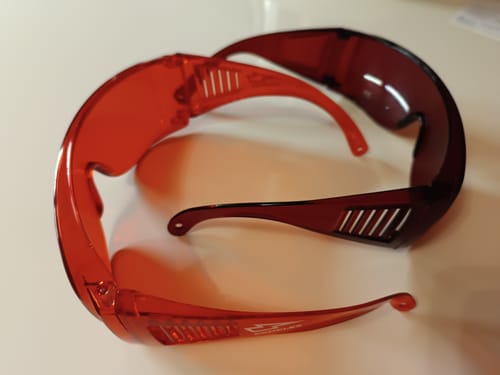 Reviewer's photo comparing their lighter Complex VisionX glasses with another, much darker pair of red glasses.