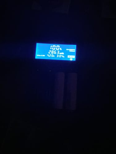 Reviewer's Samsung 35E 18650 batteries in a digital charger, with the screen showing they are 100% charged.