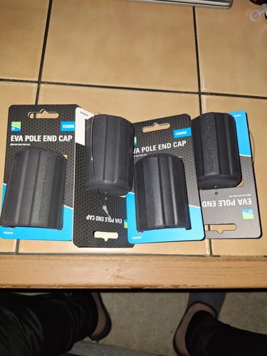 Recensent toont vier zwarte EVA Pole End Caps in de verpakking op een tafel.