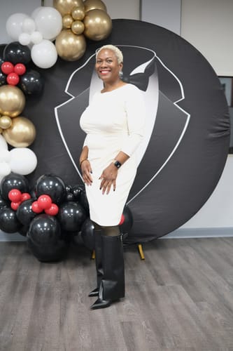 Customer poses in her black Pointed Toe Vegan Leather Knee Boots, worn with a white dress.