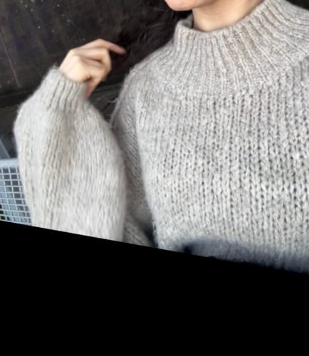 Kunde zeigt in einer Nahaufnahme den weichen, beigen „CasualCozy“ Strickpullover.