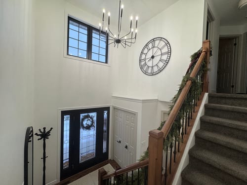 Customer's 48" Black Roman Numeral Wall Clock mounted high on the wall of a two-story entryway.