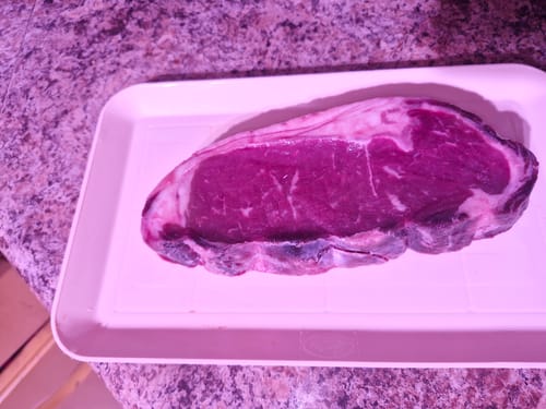 El corte crudo de Rib Eye Steak Dry Aged de un cliente en una bandeja blanca.